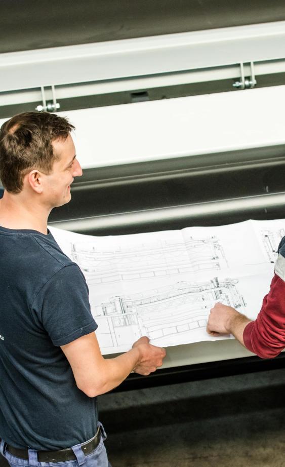 Technician and engineer discussing machine drawing